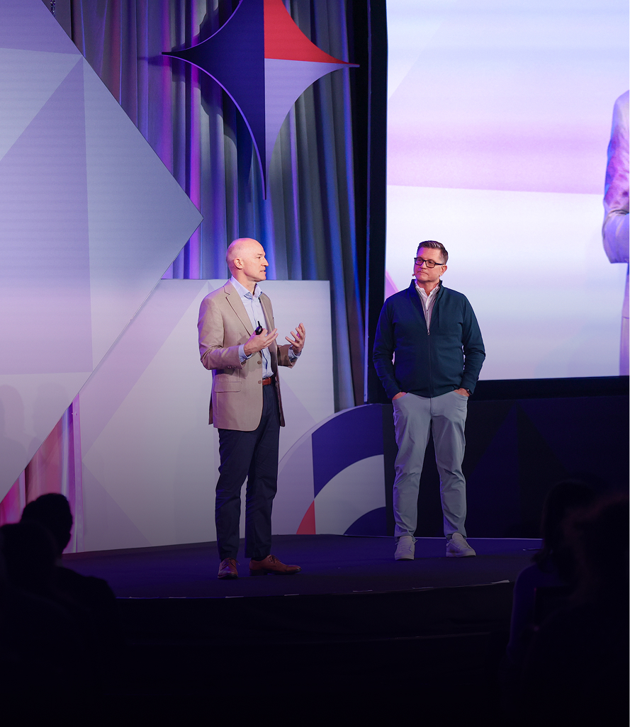 Keynote speakers presenting on main stage with branded backdrop